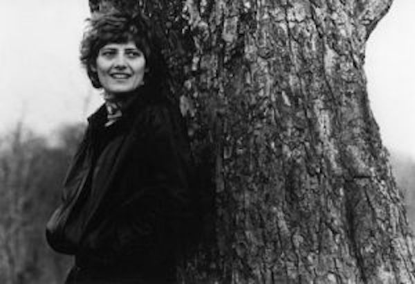 Black and white image of Petra Kelly leaning against a tree