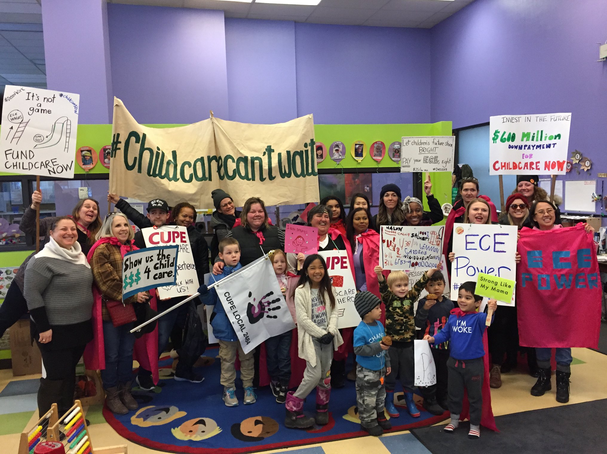 A photo of early childhood educators, adults and kids, with placards adovcating for universal child care